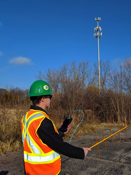 An engineer hunting interference with a SignalHawk-AOA and Yagi antenna. A cell tower is in the background.