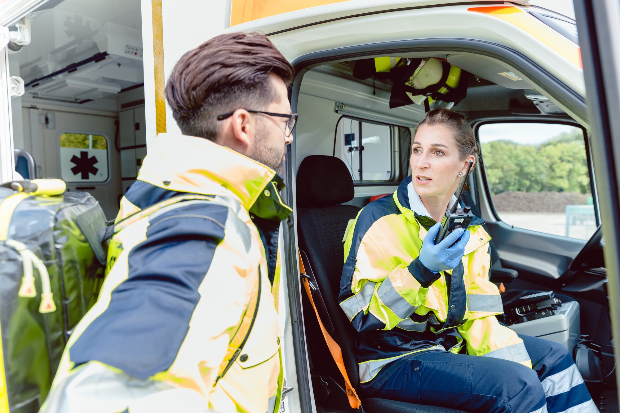 Paramedics in ambulance in radio contact with headquarters discussion deployment